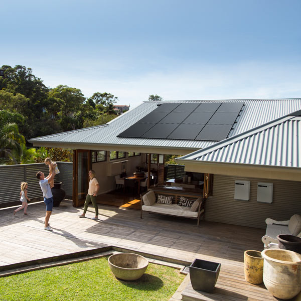 Home with solar panels and family playing in backyard